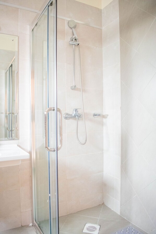 Un baño moderno con ducha de vidrio, lavamanos blanco y espejo.