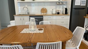 A modern kitchen with white cabinets, a wooden dining table, and white chairs.