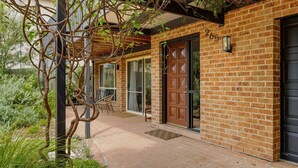 A brick building with a large wooden door, a window, and a doorbell. - Our Beach House by Experience Jervis Bay (Vincentia)