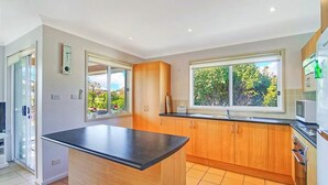 A modern kitchen with a central island, large windows, and a view of greenery.