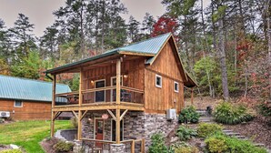 A wooden cabin with a stone foundation, a balcony, and a metal roof. - Chanterelle Cabin w/Hot Tub, Fireplace - Near Asheville! (Weaverville)