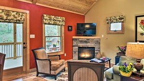 A cozy living room with a fireplace, a television, and a comfortable seating area. - Chanterelle Cabin w/Hot Tub, Fireplace - Near Asheville! (Weaverville)
