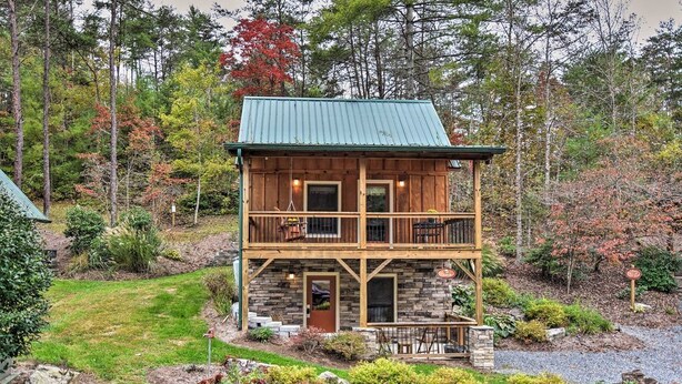 A two-story log cabin with a stone foundation, a balcony, and a front porch. - Chanterelle Cabin w/Hot Tub, Fireplace - Near Asheville! (Weaverville)