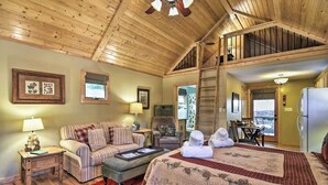 A cozy room with a bed, a sofa, a dining table, and a staircase leading to an upper level.