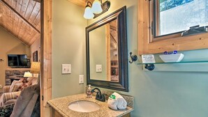 A bathroom with a granite countertop sink, a large mirror, and a shelf above the mirror.