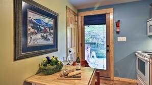 A kitchen with a wooden table, a framed painting, a bottle of wine, and a fire extinguisher. - Dog-Friendly Weaverville Cabin King Bed,Hot Tub&FP (Weaverville)