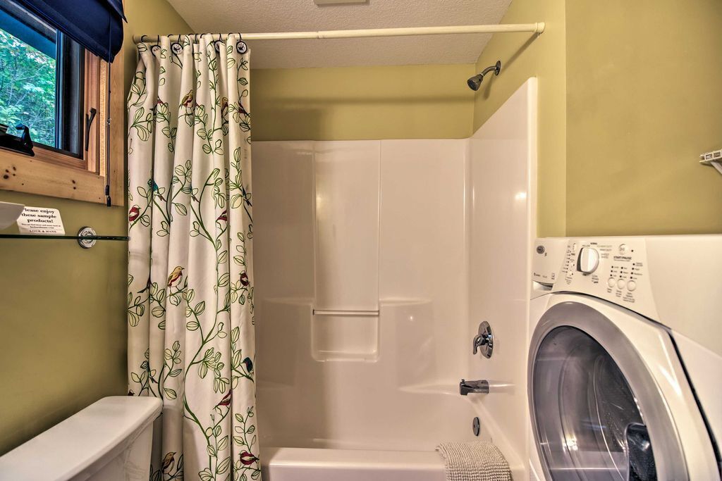 Un baño con ducha, inodoro y lavadora de carga frontal.