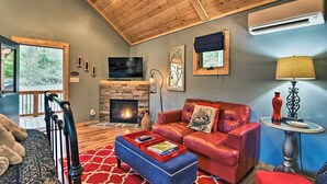 A cozy living room with a fireplace, leather sofa, and a TV. - Dog-Friendly Weaverville Cabin King Bed,Hot Tub&FP (Weaverville)
