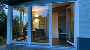 Una casa moderna con un vidrio que da a un comedor con una mesa y sillas.
