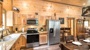 Una cucina in stile baita con mobili in legno, un frigorifero, un forno e un microonde in acciaio inossidabile.
