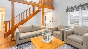 A spacious living room with a wooden staircase, a beige sofa set, and a decorative birdcage on a wooden coffee table. - Vista View | 3 Kings + 1 Queen | Hot Tub · Fire Pit · Fireplace (Galena)