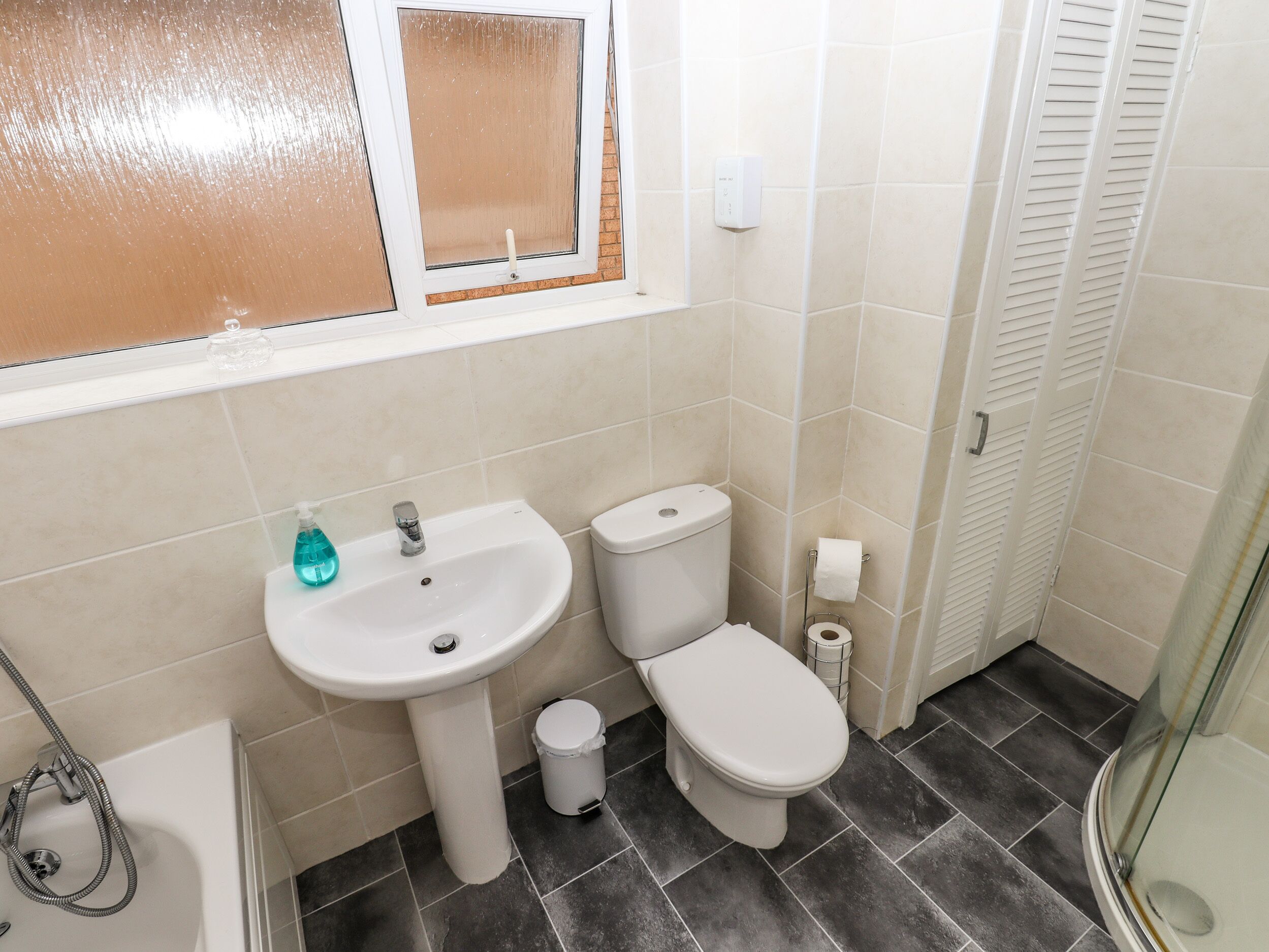 Een badkamer met wastafel, toilet en douche.