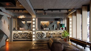 Un intérieur moderne avec un espace salon, une exposition de motos et une enseigne indiquant la présence d’un bar sur le toit.
