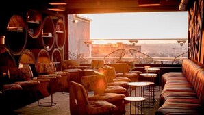 Un espace salon confortable, doté d’un canapé, de fauteuils et de tables, et offrant une vue sur la ville grâce à de grandes fenêtres.