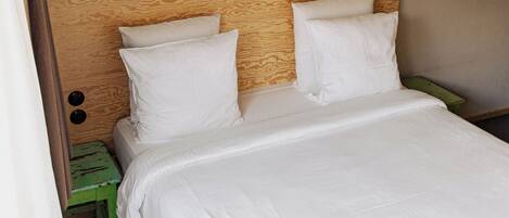 A bed with white bedding, a wooden headboard, and a green nightstand.