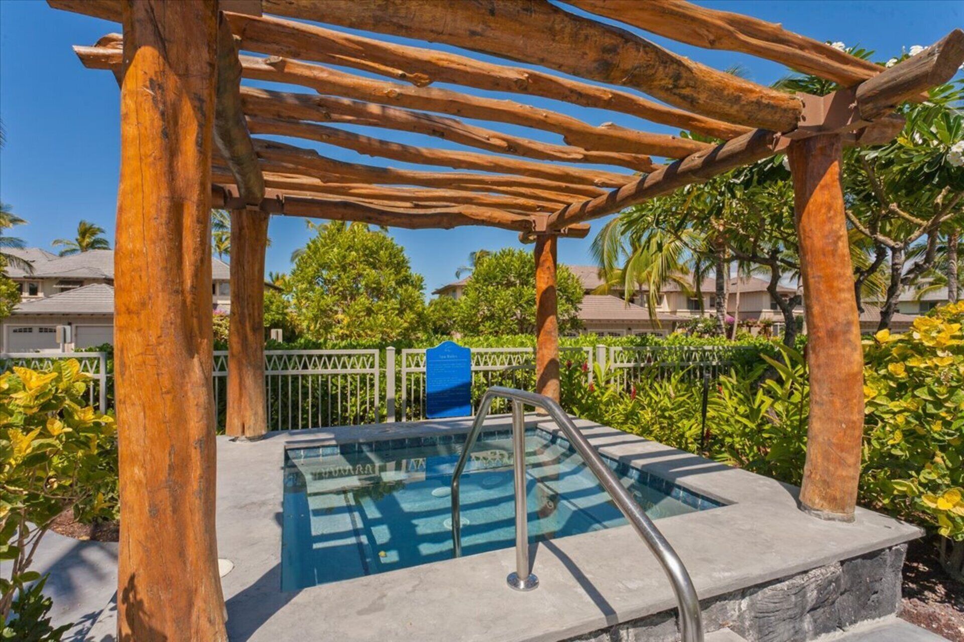 Un área de piscina con una pérgola de madera, un cerramiento de cristal y una plataforma de piedra.