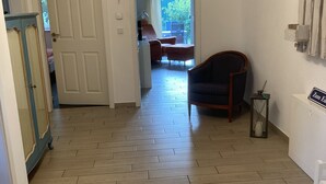 A hallway with a wooden floor leading to a dining area with a table and chairs.