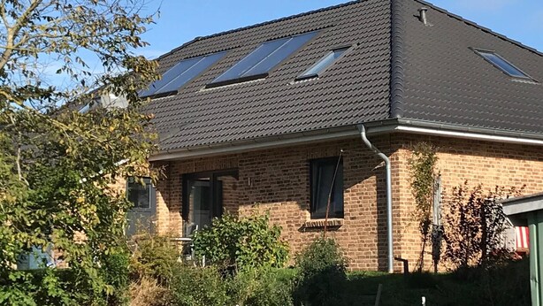 A two-story house with a sloped roof, solar panels, and a brick exterior.