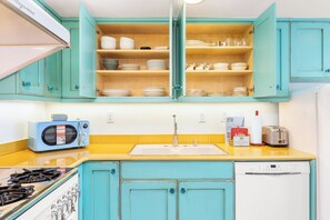 A kitchen with teal cabinets, a microwave, a sink, and a stove.