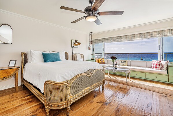 Ein geräumiges Schlafzimmer mit einem großen Bett, einem Deckenventilator, Meerblick und einem Balkon mit einer Couch.