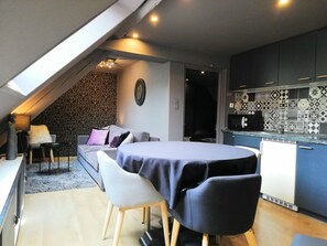 Un espacio habitable moderno estilo loft con comedor, cocina y techo inclinado con tragaluces.