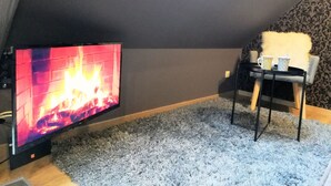 Een gezellige kamer met een open haard, een televisie, een zachte fauteuil en een kamer met een patroon op de muur.