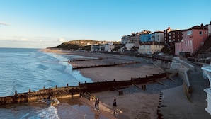 Un pueblo costero con una playa arenosa, un paseo marítimo y edificios coloridos a lo largo de la costa.
