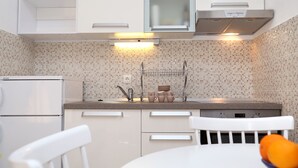 Eine moderne Küche mit weißen Schränken, einer Edelstahl-Dunstabzugshaube und einer gefliesten Rückwand.