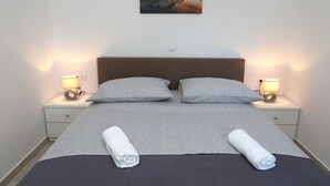 Un lit bien fait, avec deux serviettes enroulées, une tête de lit et deux lampes de chevet.