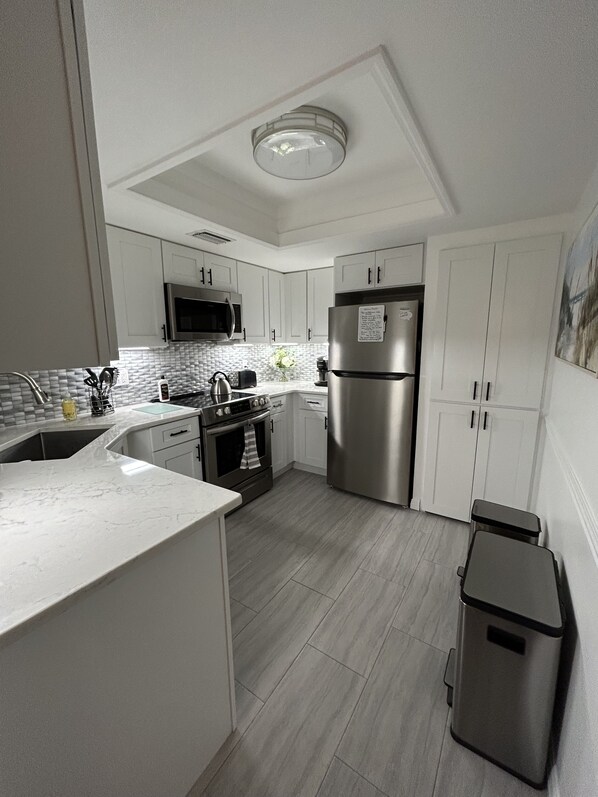 A modern kitchen with white cabinets, stainless steel appliances, and a tiled backsplash.