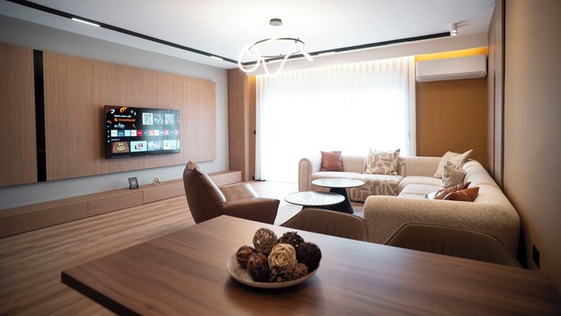 Una sala de estar moderna con una mesa de comedor de madera, un sofá y un televisor montado en la pared.