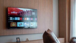 Televisor de pantalla plana montado en una pared de madera mostrando un canal deportivo.