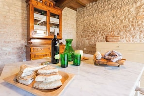 A kitchen with stone walls, a wooden cabinet, a marble countertop, and a plate of sliced bread.
