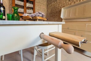 Un piano di lavoro in cucina con un matterello di legno, un bicchiere verde e una bottiglia.