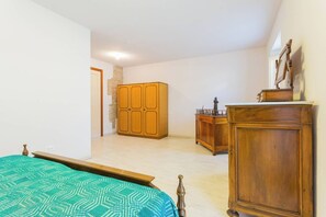 A bedroom with a bed, wooden wardrobe, and a dresser.