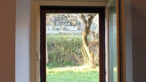 A door with a view of a grassy yard and a stone wall.