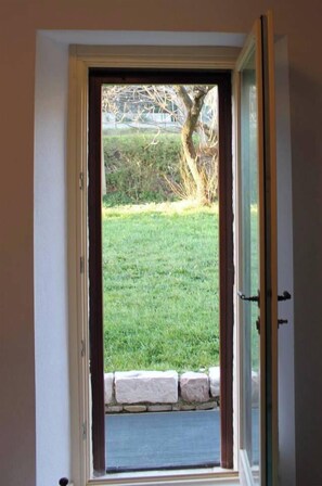 A door with a view of a grassy yard and a stone wall.