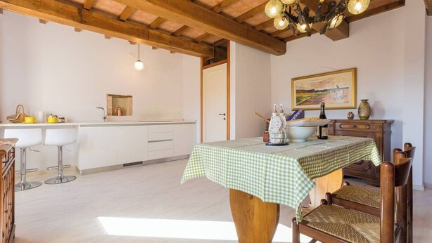 A kitchen with white cabinets, a dining table with a checkered tablecloth, and a wooden chair.