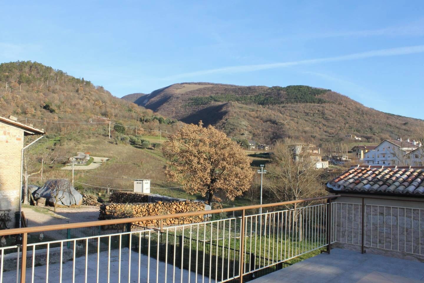 Un quartier résidentiel offrant une vue sur une colline, un arbre et un bâtiment doté d’un toit en tuiles.