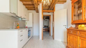 A kitchen with white cabinets, a wooden ceiling, and a chandelier. - Villa Costanzi: Breezy Terrace On The Cucco (Sigillo)