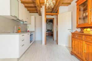 A kitchen with white cabinets, a wooden ceiling, and a chandelier.
