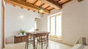 A spacious room with a wooden dining table, chairs, a sofa, and a large window. - Villa Costanzi: Breezy Terrace On The Cucco (Sigillo)