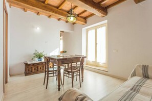 A spacious room with a wooden dining table, chairs, a sofa, and a large window.