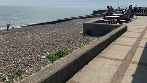 Une plage de galets, avec un ciel dégagé et une mer calme.