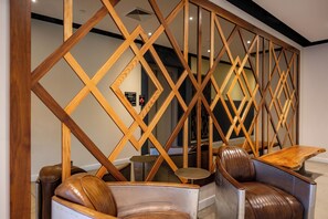 A modern interior with a geometric wooden partition, leather armchairs, and a small round table. - The Maj Hotel (Philadelphia)