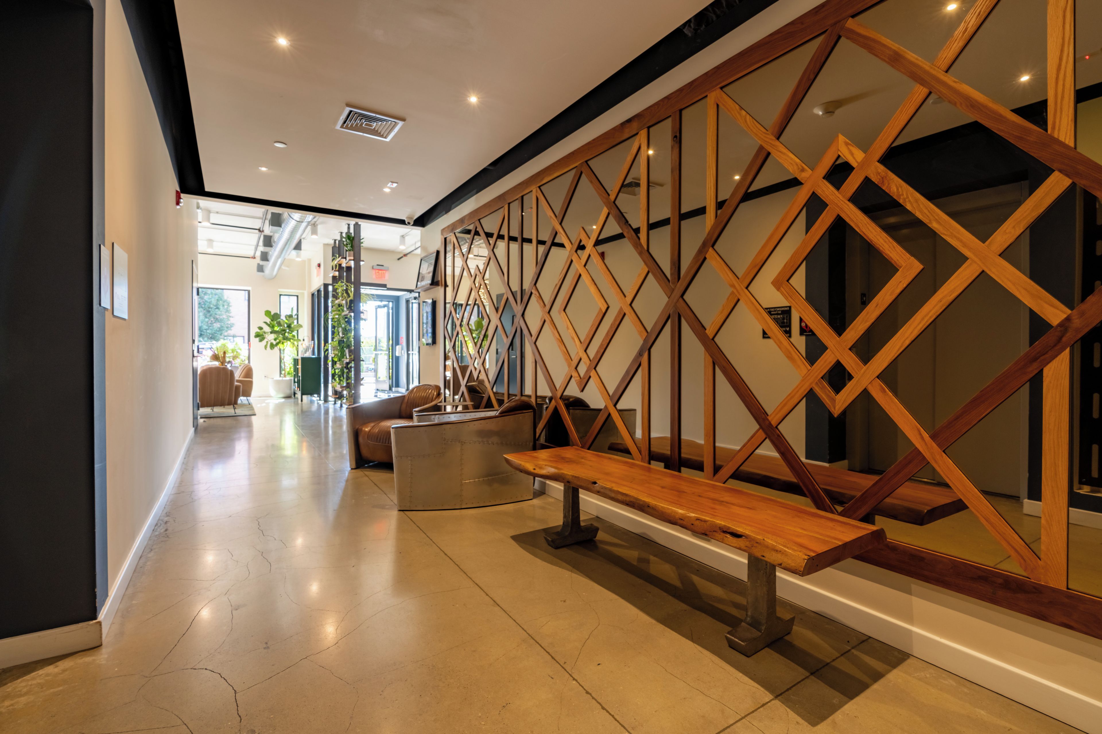 A modern interior with a wooden staircase, a bench, and a view into another room.