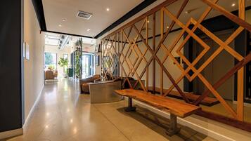 A modern interior with a wooden staircase, a bench, and a view into another room.