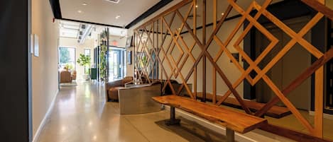A modern interior with a wooden staircase, a bench, and a view into another room.
