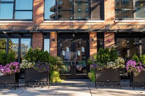 A building with a brick facade, large windows, and a black door with signage. - The Maj Hotel (Philadelphia)