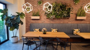 A modern interior with a wooden table, black chairs, a grey cushioned bench, and hexagonal wall-mounted lights. - The Maj Hotel (Philadelphia)